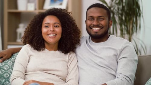 Smiling Couple Embracing on Couch Indoors