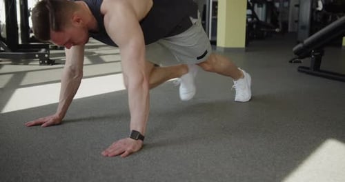 Young Muscular Athlete Works Out in Modern Gym Making Mountain Climbers Exercise