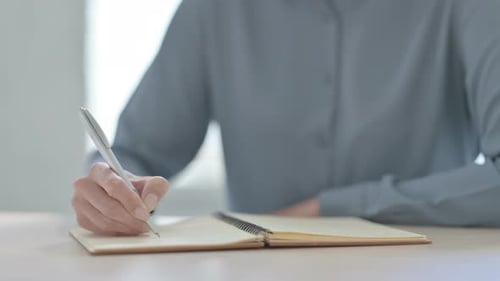 Close Up of Woman Writing on Notebook