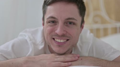 Gros plan d'un jeune homme faisant les pouces en l'air dans son lit