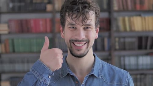 Thumbs Up By Casual Young Man at Work Looking at Camera