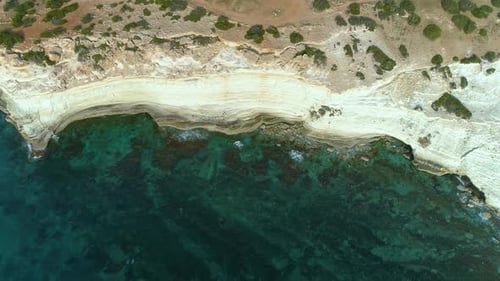Aerial Top View Footage By Drone of Ocean Blue Water and Rocks A Calm Sea Washes the Rocky Mountain