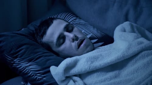 Man Sleeping in Bed with Thermometer