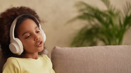 Girl Listening to Music on Headphones, Relaxing on Couch