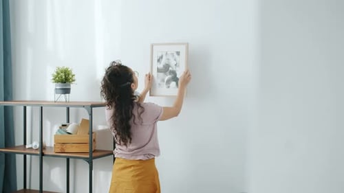 Woman Hanging Picture in Bright, Modern Apartment