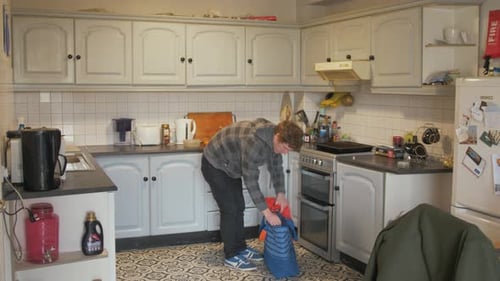 Young Man Packs Bag in Kitchen