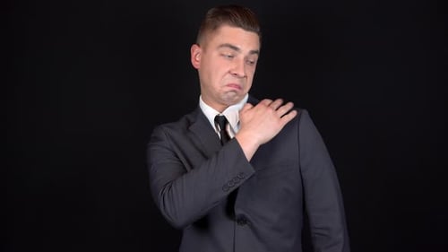 Young Adult Man in Suit Adjusts Tie