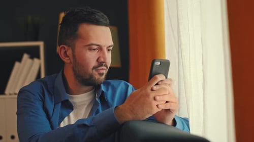 Man Texts Message By Window