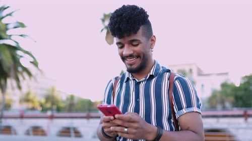 Happy Young Man Using Touch Mobile Phone Outdoor on City Street