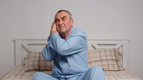 Man with Ear Pain Sitting on Bed
