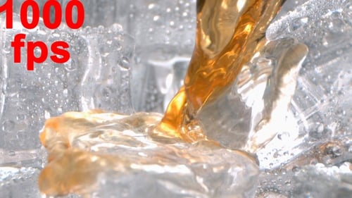 Cognac Alcohol Drink Is Flowing And Pouring On Ice In A Glass In High Speed