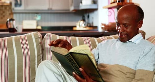 Senior man reading book in living room