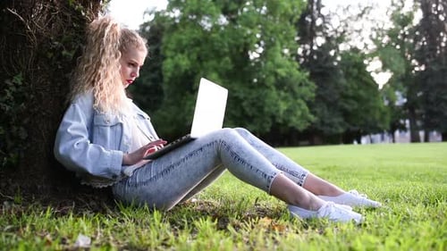 Woman Using Laptop Relaxing in City Park