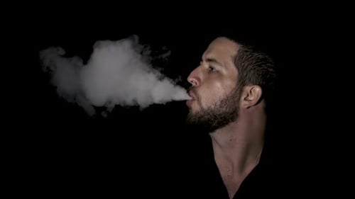 Man Exhaling a Cloud of Vapor on Black Background