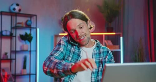 Un gars avec une boucle d'oreille dans le nez tape sur un ordinateur portable lors d'une conversation mobile