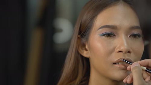 Stunning model getting lipstick put on in the studio by a professional makeup artist