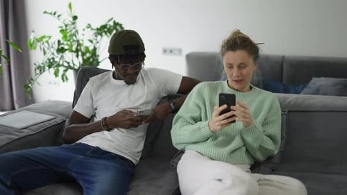 Couple Using Smartphones on Couch in Living Room