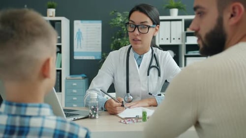 Pediatrician Friendly Woman Speaking with Young Man and Little Boy in Hospital Room