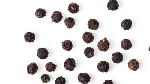 Dry Black Peppercorns Scattered on White Surface