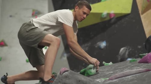 Man Climbing Rock Wall at Indoor Climbing Gym