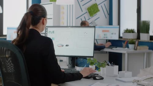 Woman Working at Computer in Busy Office