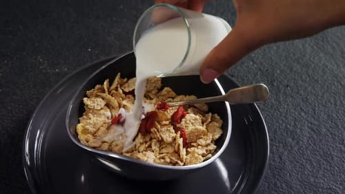 Pouring Milk Over Golden Flakes and Berries