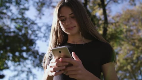 An Attractive Young Lady Using a Phone in Town. Medium Shot