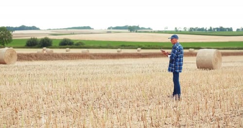 Farmer with Tablet in Harvested Field