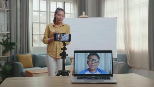 Une enseignante tourne une vidéo par smartphone et a un appel vidéo sur un ordinateur portable tout en enseignant l'anglais