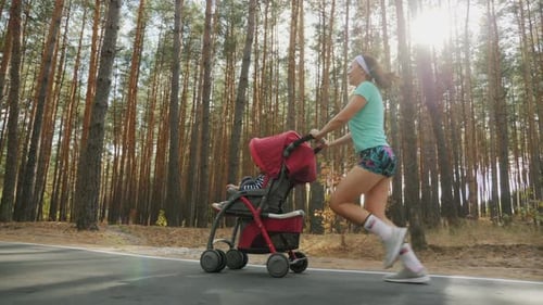 Running Woman with Baby Stroller on the Road in Forest