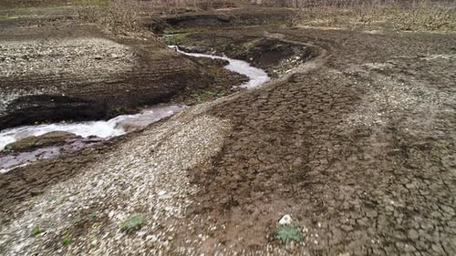 Small river flows through dry clay area