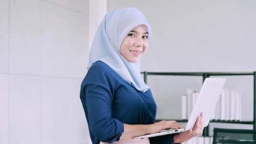 Retrato de joven mujer de negocios musulmana asiática con laptop.
