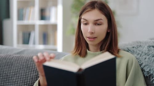 Woman Reading Book Relaxing on Sofa