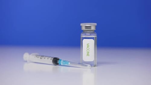 Vaccine Vial and Syringe on Blue Background