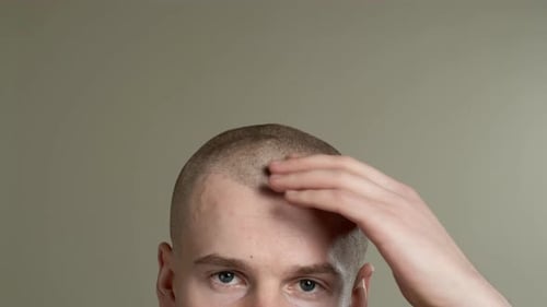 Young Man with Short Hair Rubbing Head Close Up