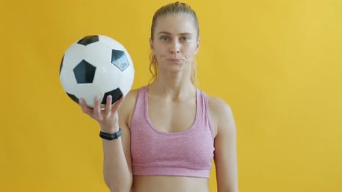 Portrait of Young Sportswoman Holding Football Showing Red Card and Looking at Camera