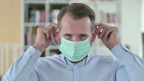 Man Adjusting Green Medical Face Mask Indoors