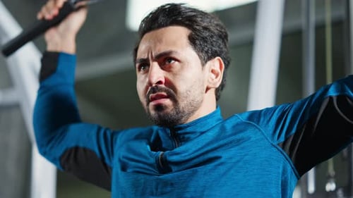 4K Caucasian man bodybuilder pulling weight lifting machine at gym.