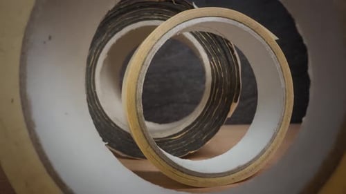 Paper Tape Rolls on Cardboard Surface Against Black Wall