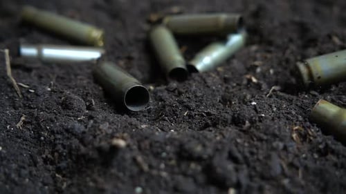 Bullet casings fall to the ground. Slow motion.