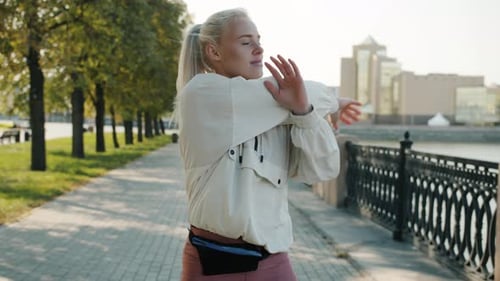 Beautiful Young Woman Working Out Outside Training Arms and Smiling in River Embankment