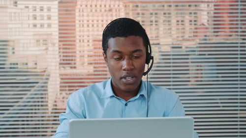 Young Man Talking on Headset in Modern Office