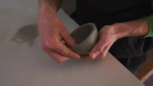 Close up view of male potter working on clay pots at pottery studio
