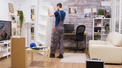 Male Worker in Coverall Picks Up Assembled Furniture