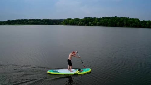 Man Paddleboarding on Lake at Sunrise Aerial View