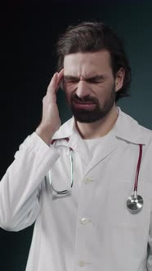 Concerned Male Doctor Rubs Temple, Puts on Glasses