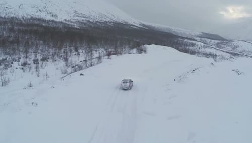 Aerial View of Car Driving on Snowy Mountain Road