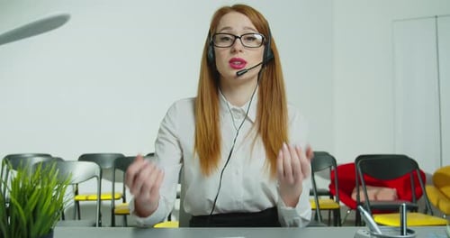 Une femme d'affaires, formatrice, enseignante et tutrice dans un casque avec microphone, regarde des enregistrements de caméra en ligne