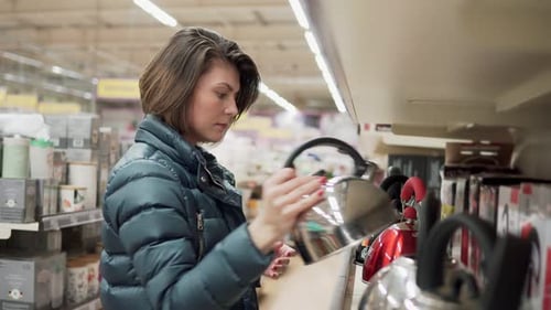 Beautiful Brunette Woman in Coat Chooses a Kettle in the Shop of Home Appliances