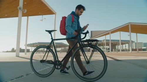 Millennial Youth Walk with Smartphone and Bike